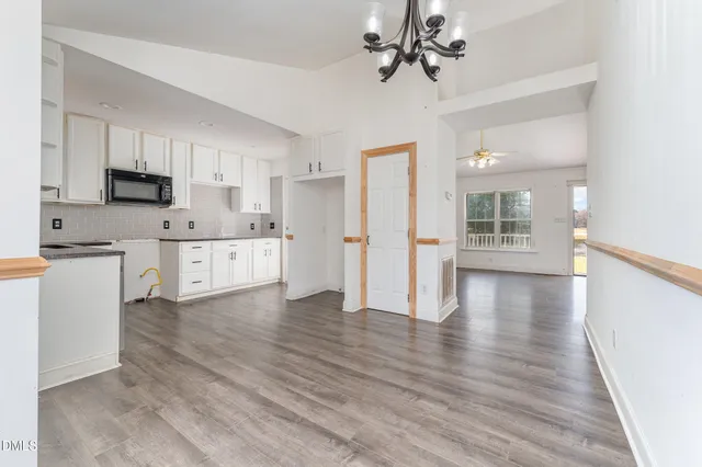a view of a kitchen with a sink a refrigerator cabinets and wooden floor