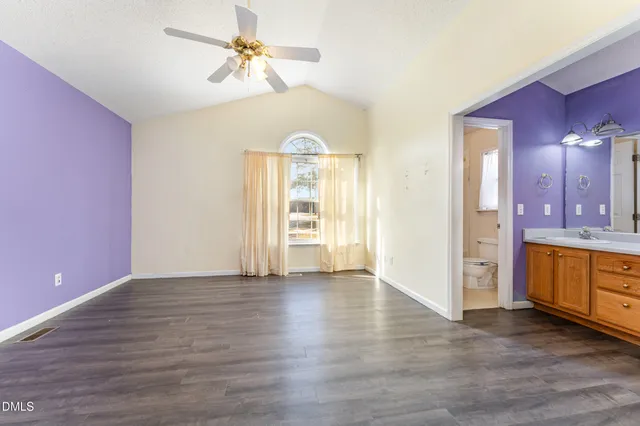 a view of an empty room with a kitchen and a window