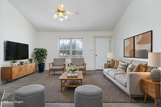 a living room with furniture a flat screen tv and a large window