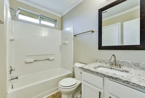 a bathroom with a granite countertop toilet a sink and a mirror