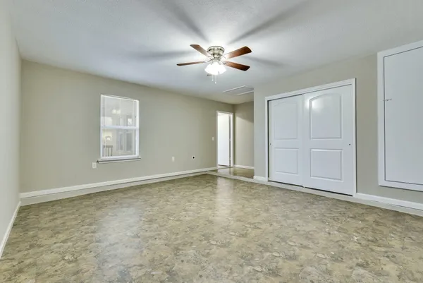 a view of an empty room with window and chandelier fan