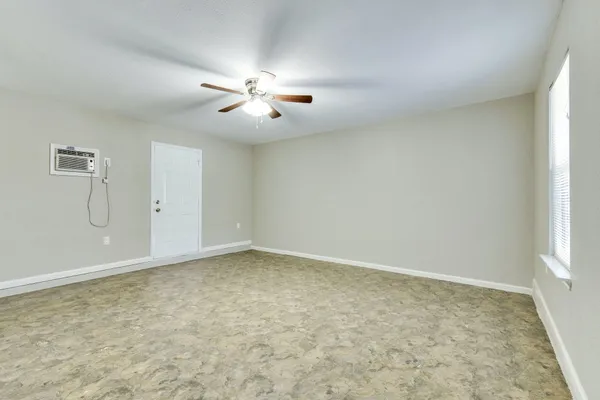 a view of an empty room and chandelier fan