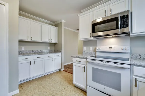 a kitchen with granite countertop white cabinets and stainless steel appliances