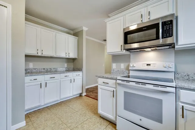 a kitchen with granite countertop white cabinets stainless steel appliances and sink