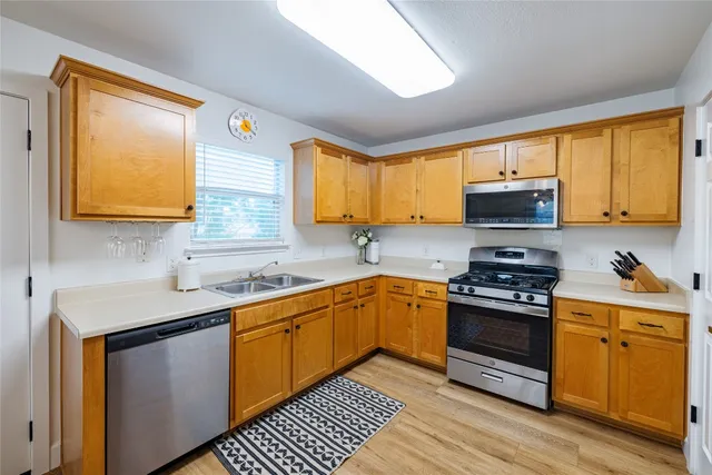 a kitchen with stainless steel appliances granite countertop wooden cabinets a stove a sink and a window