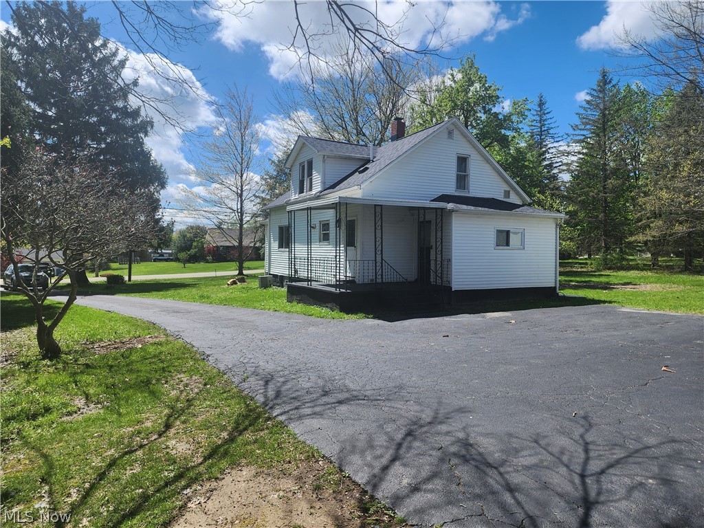 3187 Grenfall Road Barberton, OH 44203 - Photo 15 of 17 White siding exterior featuring a covered porch with wrought iron railing, a gabled roof, and a paved driveway