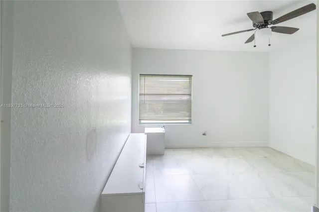 an empty room with a window and a ceiling fan