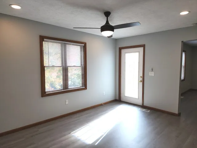 a view of an empty room with wooden floor and a window