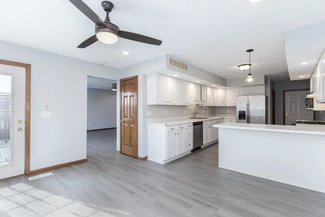 a large kitchen with cabinets wooden floor and stainless steel appliances