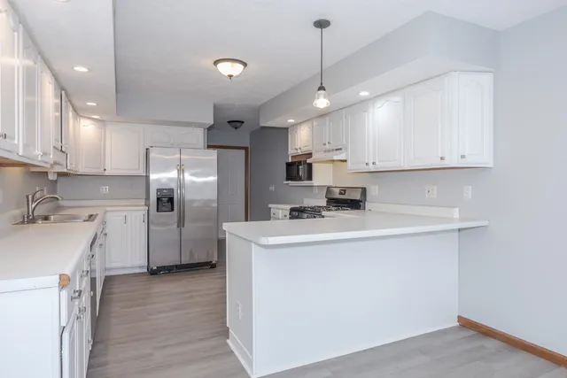 a kitchen with stainless steel appliances granite countertop a sink a stove a refrigerator and island with wooden floor