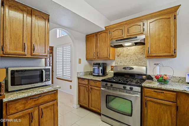 a kitchen with stainless steel appliances granite countertop a sink a stove a dining table and chairs