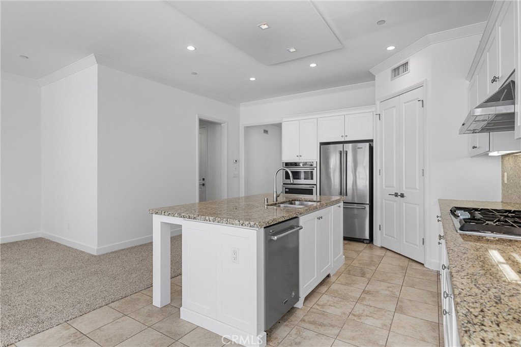 82 Meander Irvine, CA 92620 - Photo 5 of 32 a kitchen with stainless steel appliances granite countertop a stove a refrigerator a sink and white cabinets