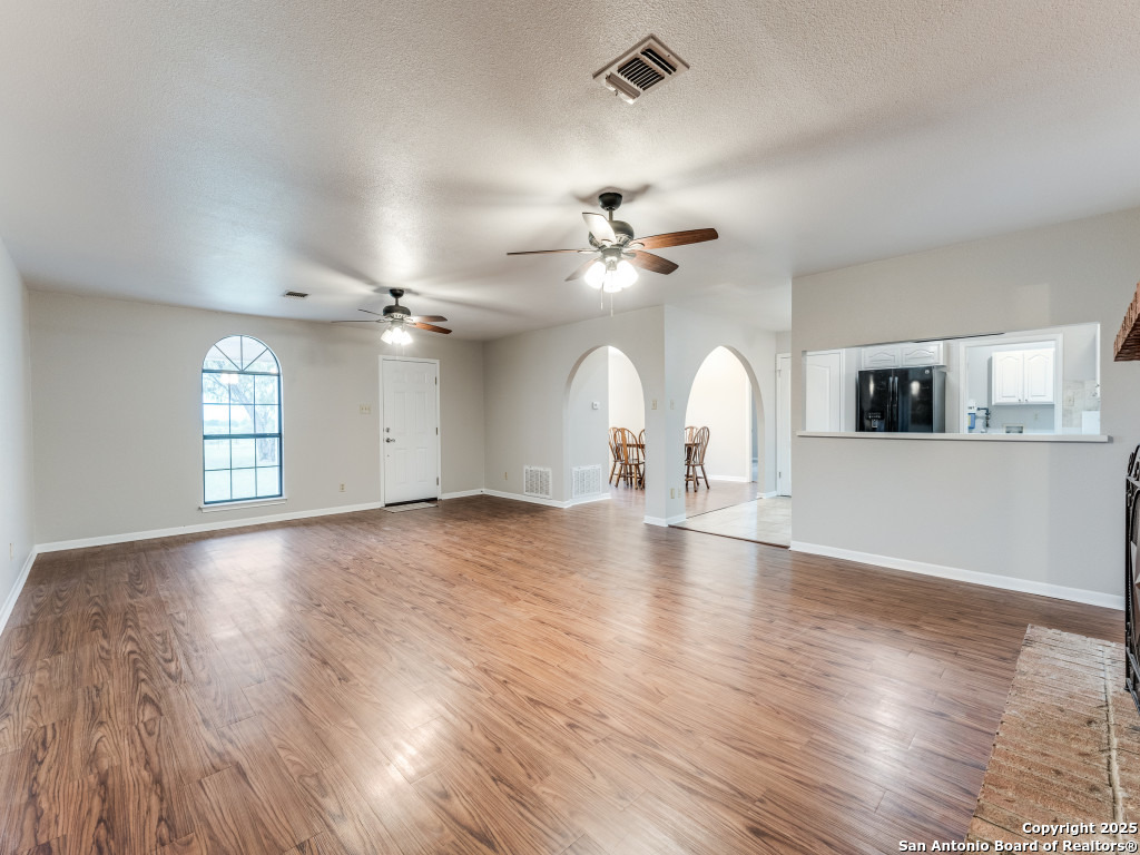 315 Simon Road Pleasanton, TX 78064 - Photo 12 of 37 an empty room with wooden floor chandelier fan and windows