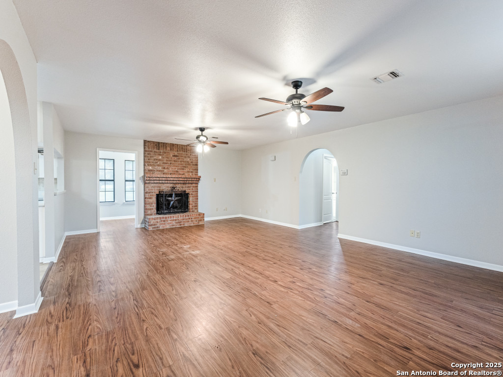 315 Simon Road Pleasanton, TX 78064 - Photo 13 of 37 a view of a livingroom with a fireplace a chandelier and wooden floor