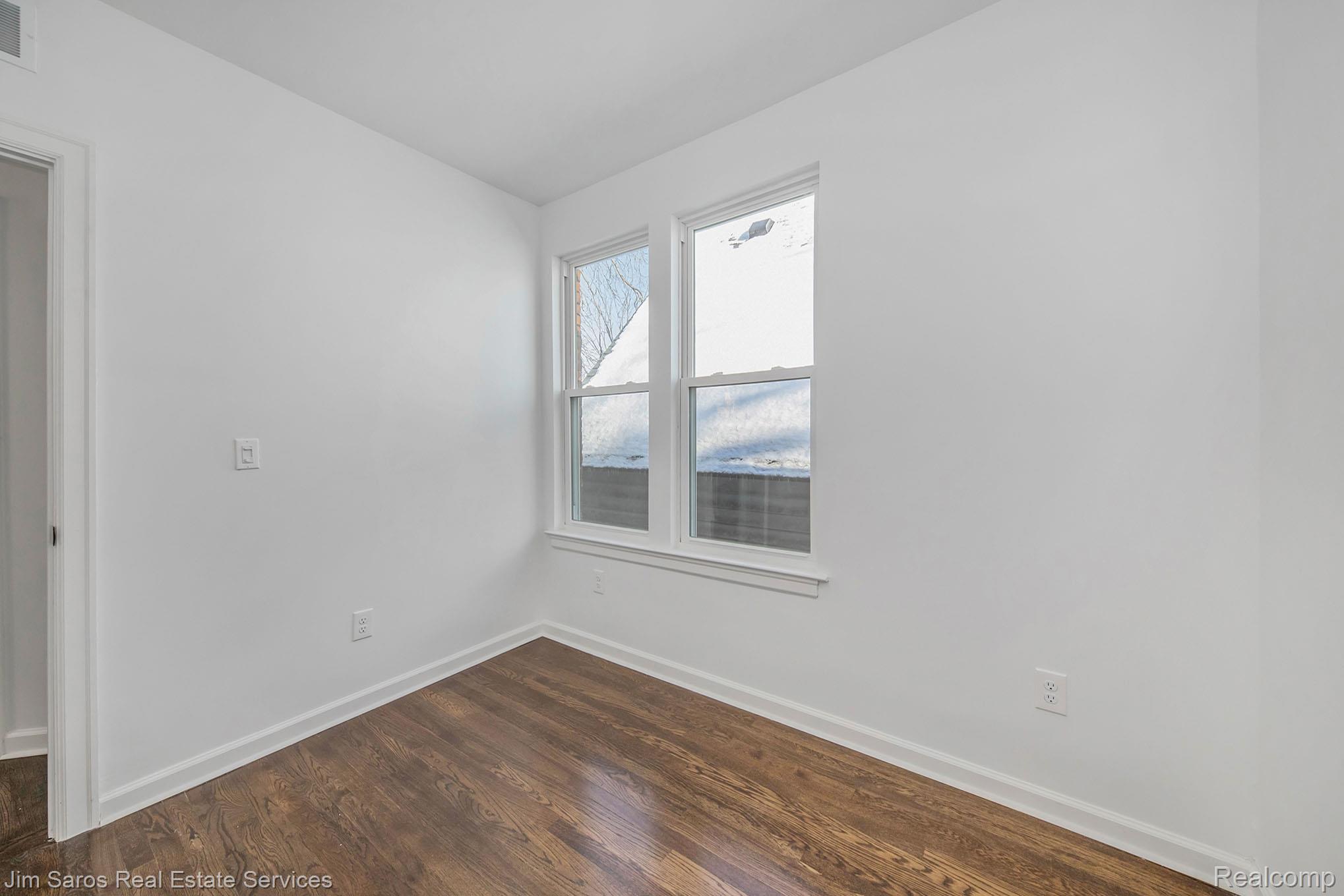 249 Custer Street Detroit, MI 48202 - Photo 14 of 22 White walls with bright trim, wood-finish flooring, and a double-hung window