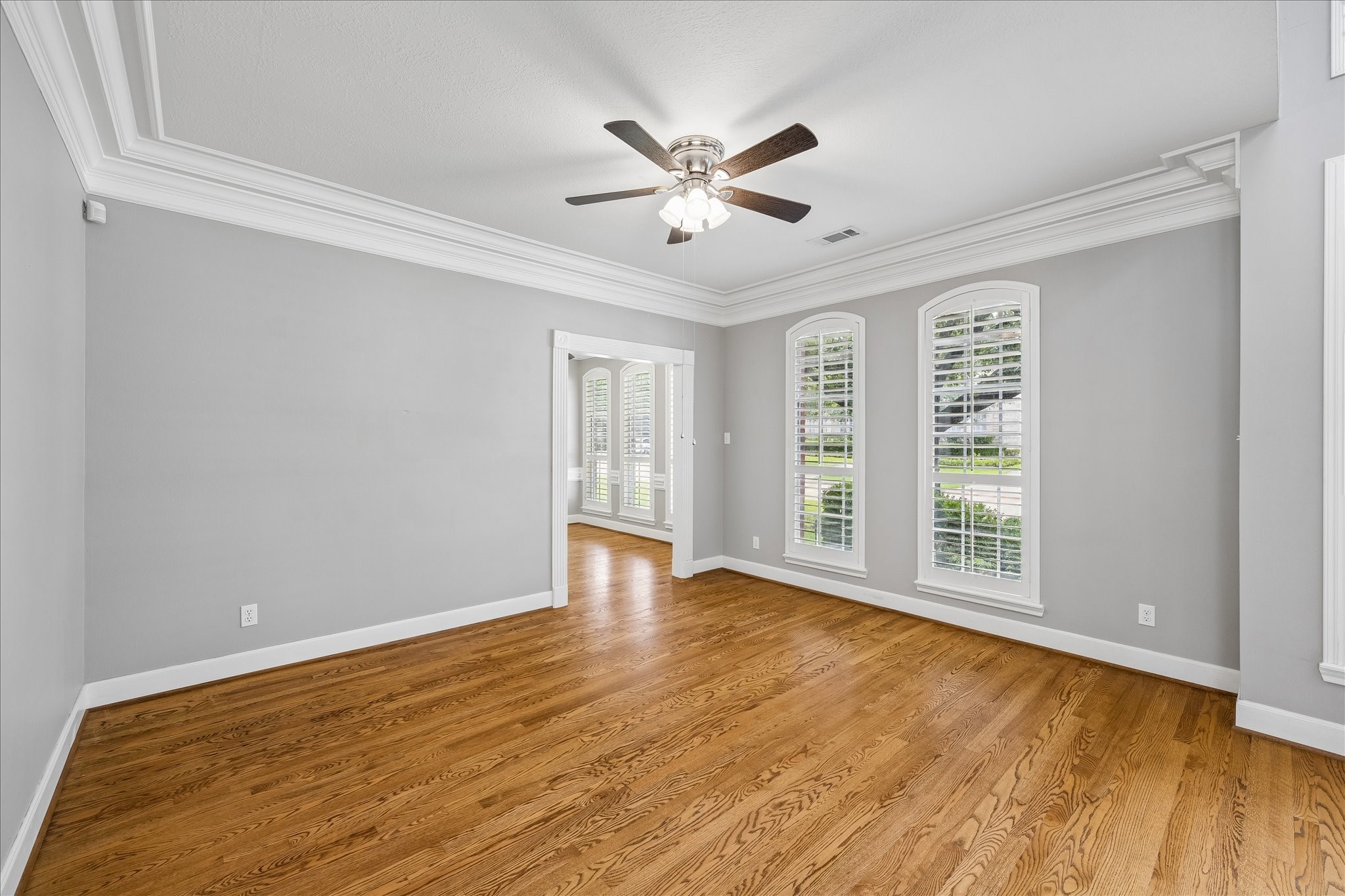 7915 Huddersfield Court Spring, TX 77379 - Photo 11 of 37 Formal living room with hardwood floors, fresh paint, crown molding, and tall shuttered windows that bring in natural light from the front of the home. The cased opening straight ahead leads to a home office with closet