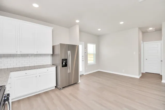 a large white kitchen with kitchen island a sink wooden floor and glass doors