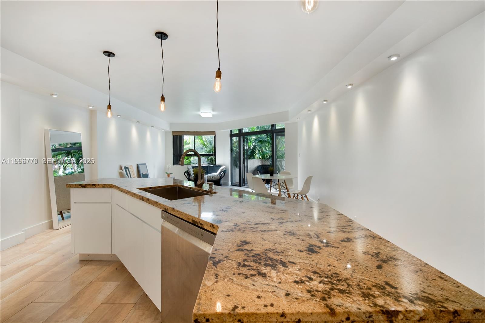 181 Crandon Boulevard, Unit 104 Key Biscayne, FL 33149 - Photo 5 of 28 a large kitchen with kitchen island a stove a sink a counter space and a chandelier
