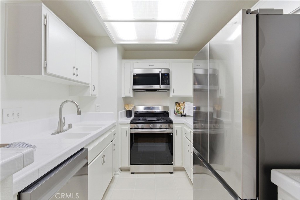 7735 Briarglen Loop, Unit I Stanton, CA 90680 - Photo 12 of 32 a kitchen with stainless steel appliances granite countertop a stove and a refrigerator