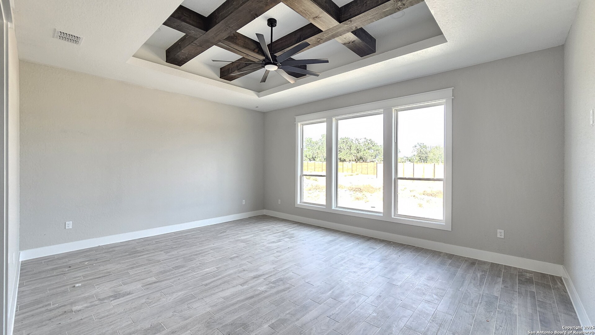 699 James Way Castroville, TX 78009 - Photo 12 of 31 an empty room with wooden floor fan and windows