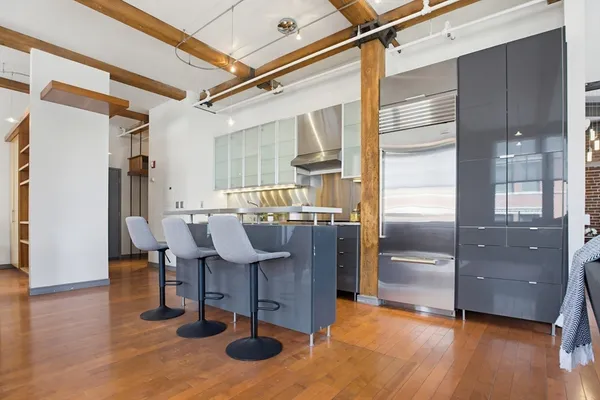 a living room with couch chairs and kitchen view with wooden floor