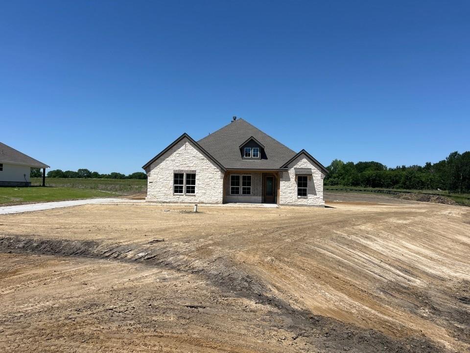 Newly constructed single-story residence featuring a light-colored stone facade and a dark shingle roof