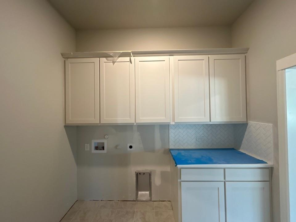 8935 County Road 623 Blue Ridge, TX 75424 - Photo 13 of 17 Laundry space featuring white shaker-style cabinetry, a herringbone tile backsplash, and a counter-height base cabinet