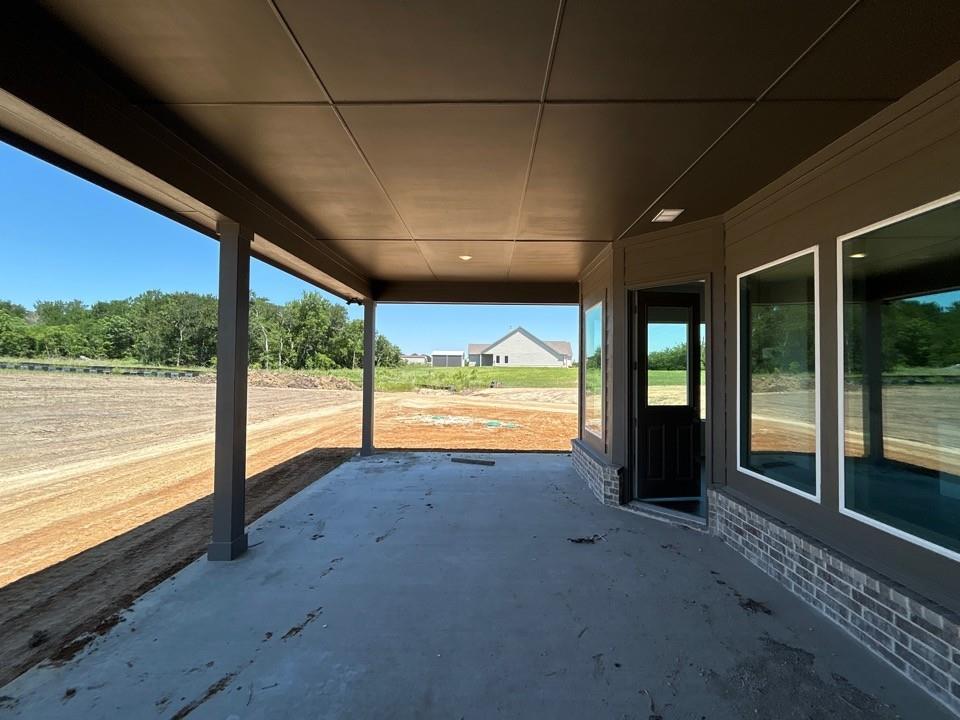 8935 County Road 623 Blue Ridge, TX 75424 - Photo 15 of 17 Covered concrete patio featuring recessed lighting, a framed glass door, and large windows with white trim, all set against a horizontally paneled exterior with a brick base