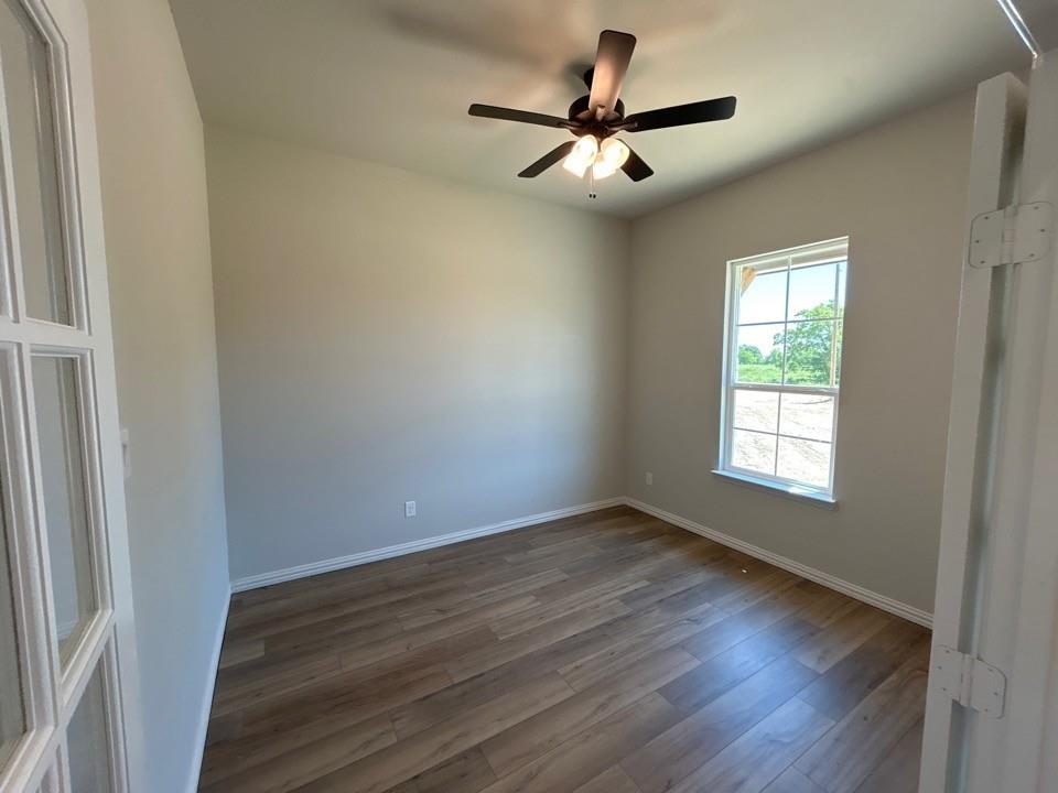 8935 County Road 623 Blue Ridge, TX 75424 - Photo 4 of 17 Bright interior space featuring wood-finish flooring, a ceiling fan with integrated lighting, and a window with white trim