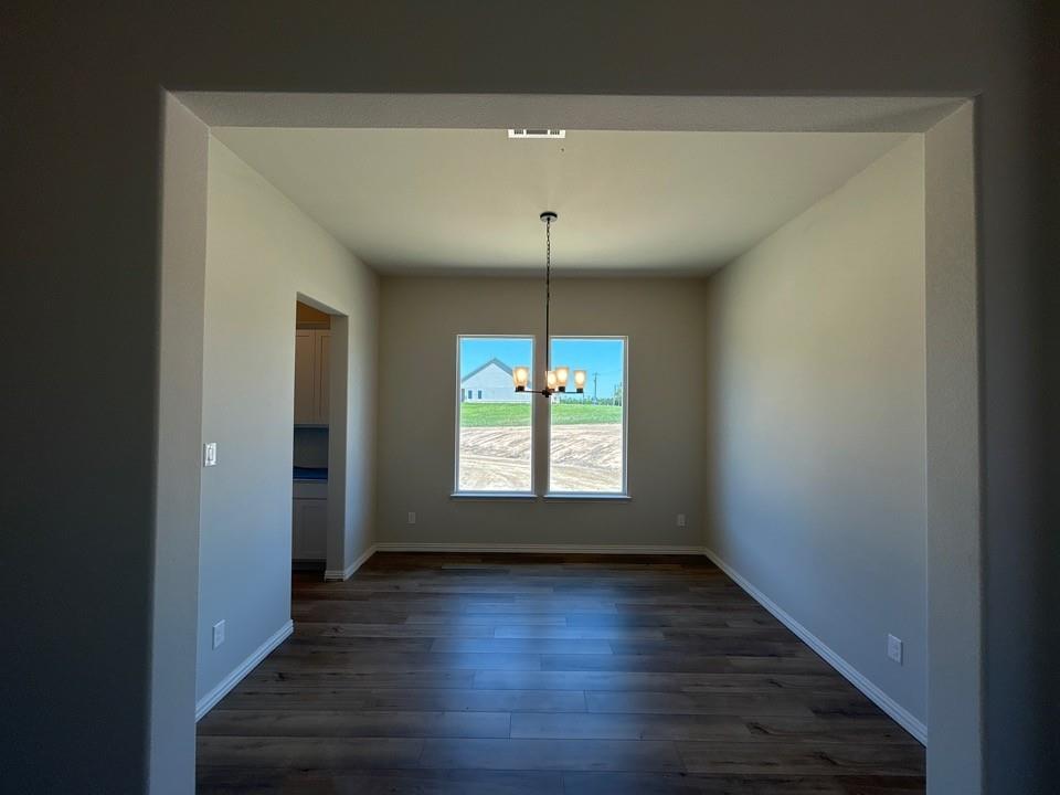 8935 County Road 623 Blue Ridge, TX 75424 - Photo 5 of 17 Spacious room featuring wood-finish flooring, two windows, and an overhead chandelier with four light sources