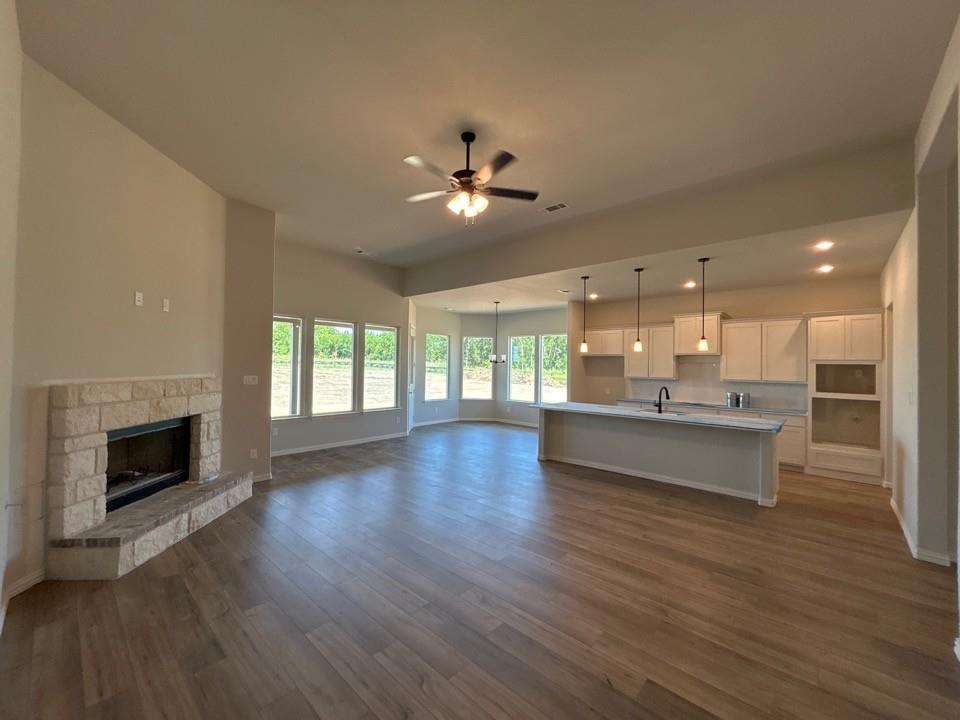 8935 County Road 623 Blue Ridge, TX 75424 - Photo 6 of 17 Open-concept living space featuring wood-finish flooring, a stone fireplace, and a kitchen island with pendant lighting