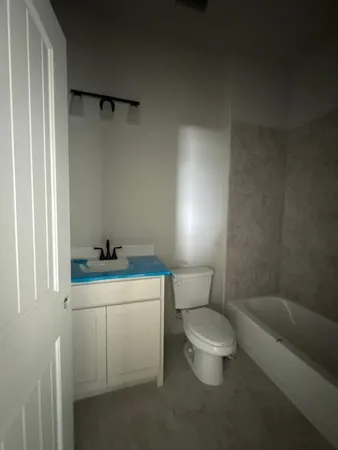 a white toilet sitting next to a bathroom sink and vanity