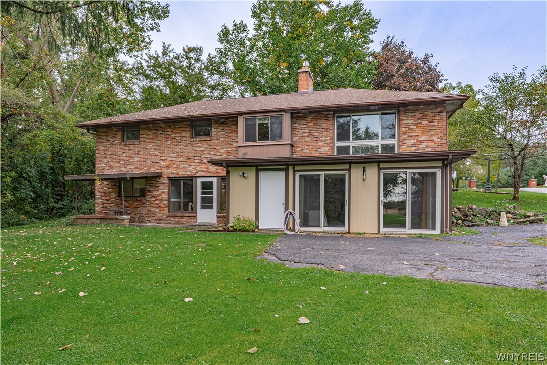 Mature trees frame a classic brick exterior complete with a spacious green yard.