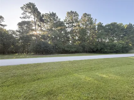 a view of yard with swimming pool and trees in the background