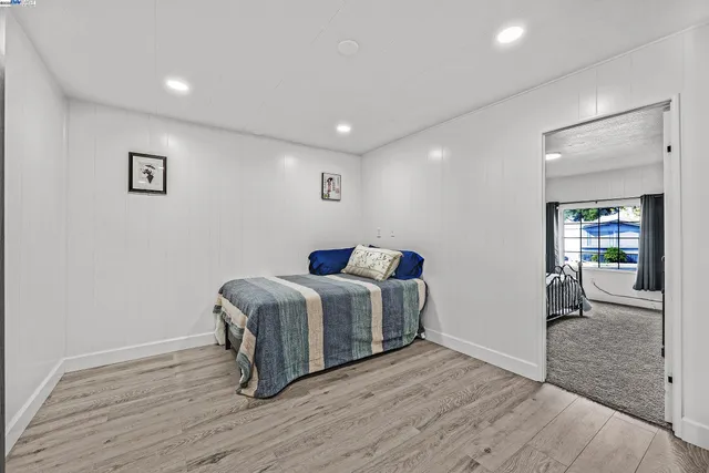 a spacious bedroom with a bed and wooden floor