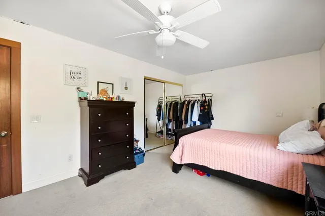 a spacious bedroom with a bed a chandelier and windows