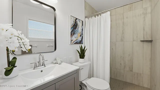 a bathroom with a sink a toilet and shower curtain