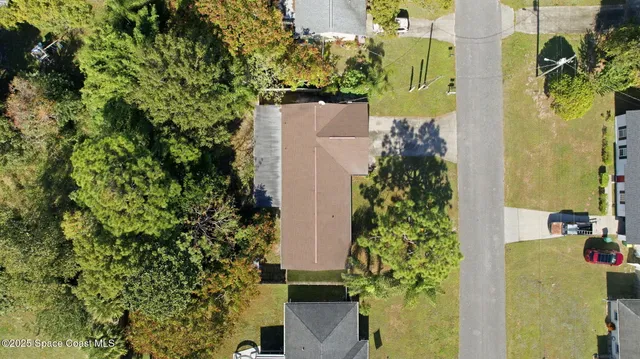 an aerial view of residential house with outdoor space and trees all around