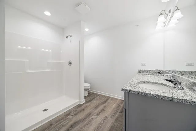 a bathroom with a granite countertop sink a mirror and shower