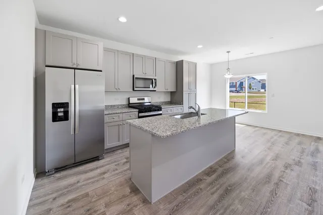 a kitchen with stainless steel appliances granite countertop a refrigerator a stove a sink and a microwave