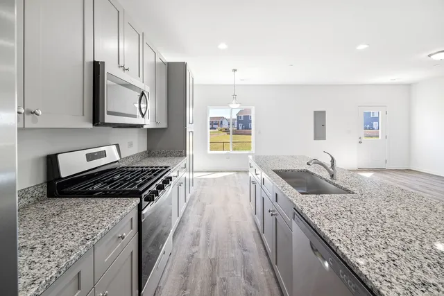 a kitchen with granite countertop stainless steel appliances window a sink and cabinets
