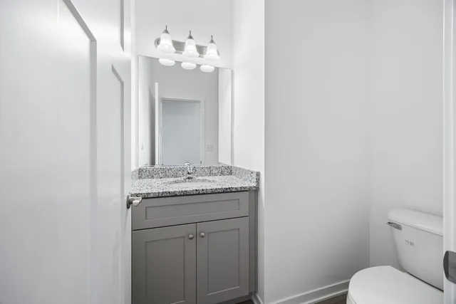a bathroom with a granite countertop sink a toilet and a mirror