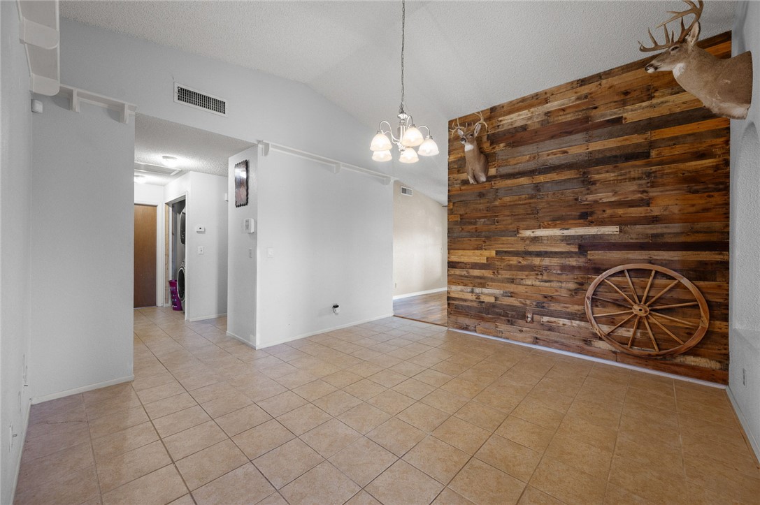 4100 North Skylark Road Kingman, AZ 86409 - Photo 36 of 60 Empty room featuring wooden walls, lofted ceiling, light tile patterned floors, a chandelier, and a textured ceiling