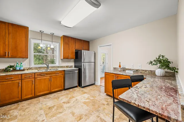 a kitchen with stainless steel appliances granite countertop wooden cabinets a stove top oven a sink and dishwasher