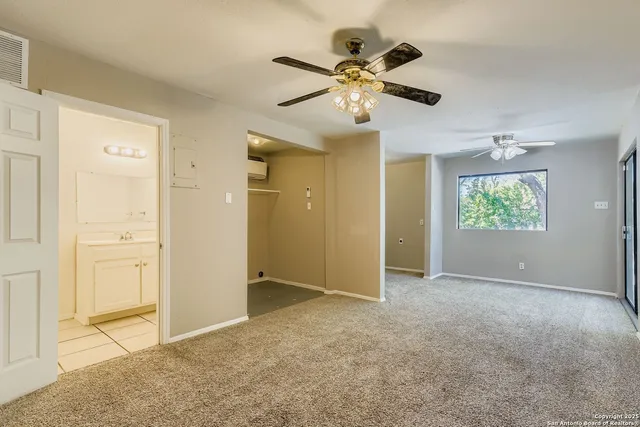 an empty room with windows and fan