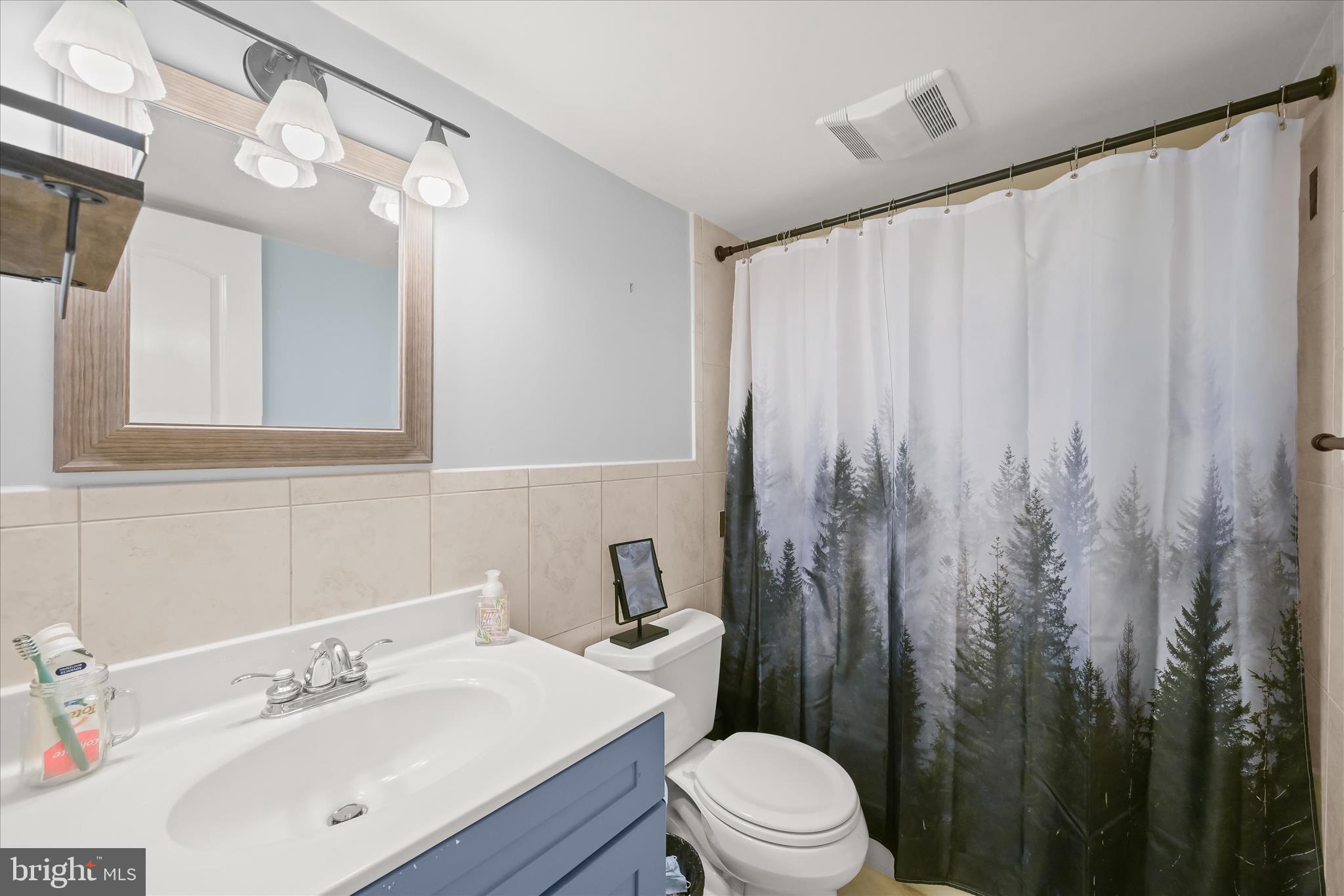 10851-10859 Amherst Avenue, Unit 202 Silver Spring, MD 20902 - Photo 22 of 32 a bathroom with a sink a toilet and shower curtain
