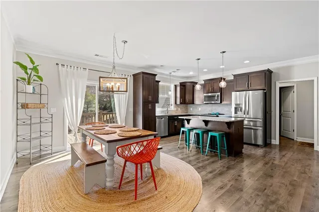 a kitchen with stainless steel appliances kitchen island granite countertop a dining table chairs and granite counter tops