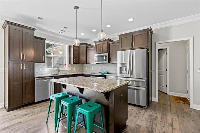 a kitchen with kitchen island a counter top space stainless steel appliances and wooden floor