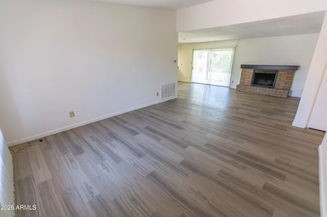 an empty room with wooden floor fireplace and windows