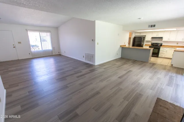 an empty room with wooden floor and windows